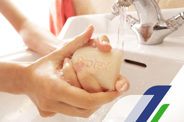 Foco na mão de uma pessoa usando o sabonete Protex para eliminar as bactérias nas mãos