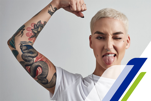 Mulher com o braço tatuado levantado piscando o olho e com a língua de fora