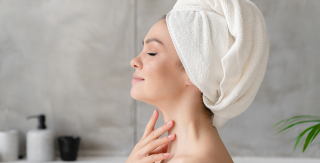 Mulher com toalha na cabeça, relaxando após o banho enquanto aproveita a hidratação na pele proporcionada pelo sabonete de glicerina